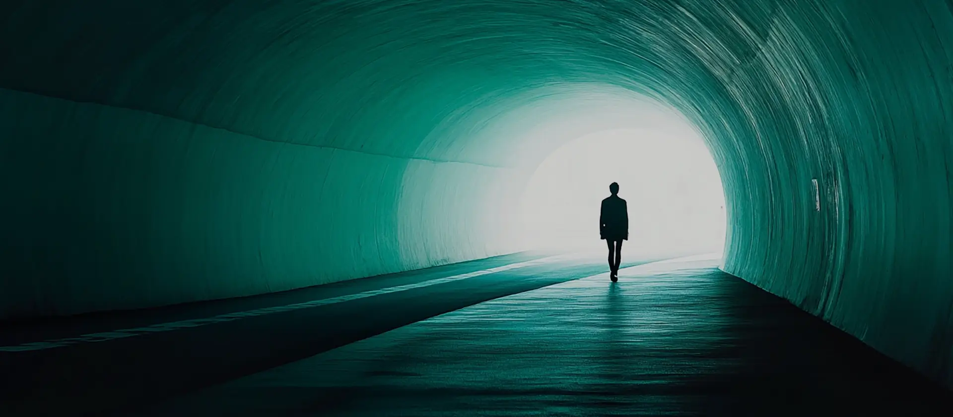 A lone figure walking through a dimly lit tunnel toward a light, symbolizing the journey through grief and finding closure.