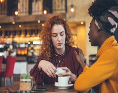 Two women having a heartfelt conversation over coffee in a cozy cafe."